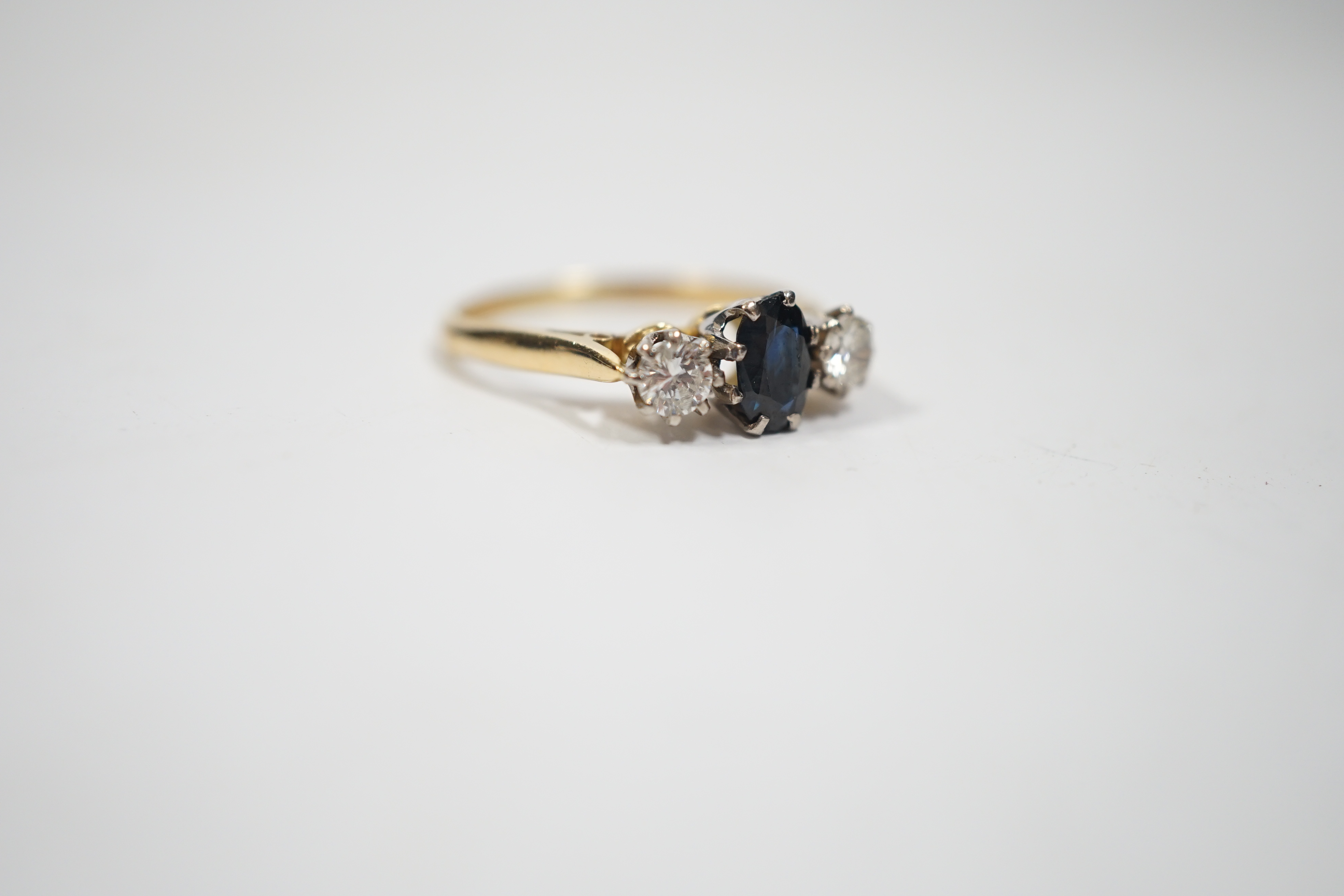 An 18ct, sapphire and diamond set three stone ring, size N, gross weight 2.8 grams.